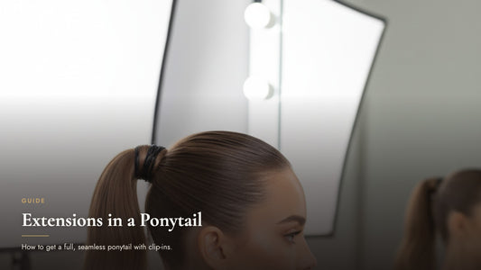 Woman with a sleek high ponytail viewed from the side at a vanity mirror, cover image for how to wear clip-in extensions in a ponytail